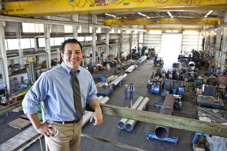 hispanic man owner of a sheet metal factory stanidng above factory floor 1 1
